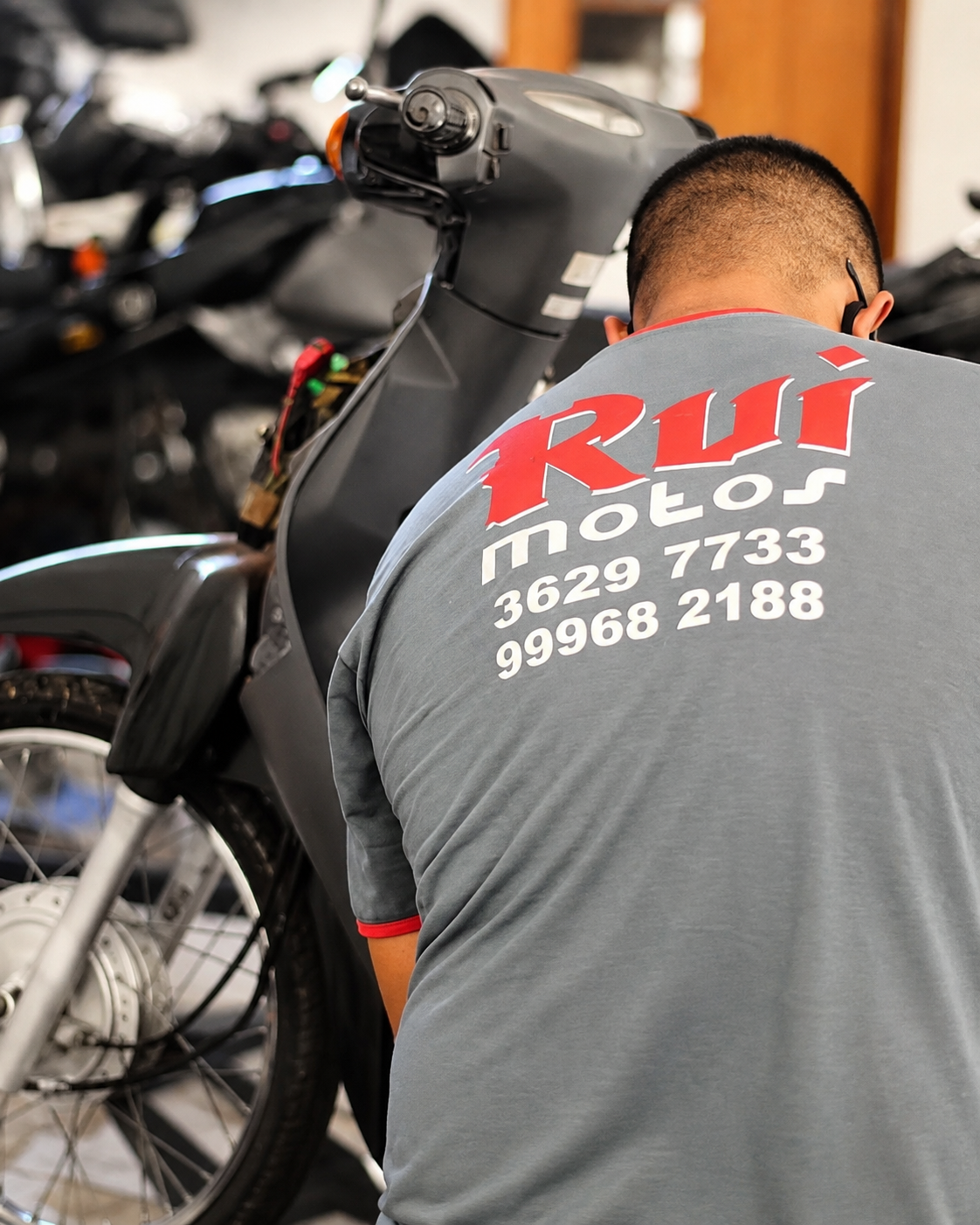 Mecânico da equipe Rui Motos, com uniforme da oficina, realizando manutenção em uma motocicleta